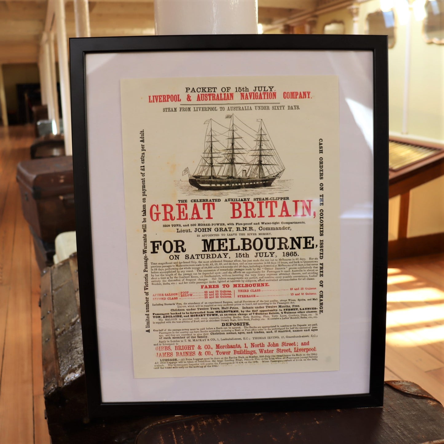 A framed poster reproduction of a 19th-century Victorian advert for the SS Great Britain, displaying a black and white illustration of the ship and text detailing its route from Liverpool to Melbourne.